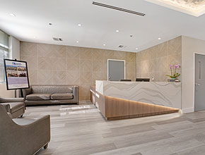 A wooden floored lobby with a number of couches near the entrance