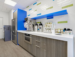 A simple kitchen area with one wall lined with cabinetry, a fridge, and a trash can.